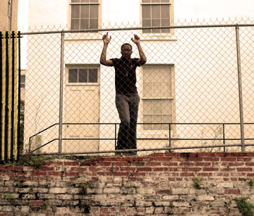 Tabitha behiind a wire fence, her hands up against the fence