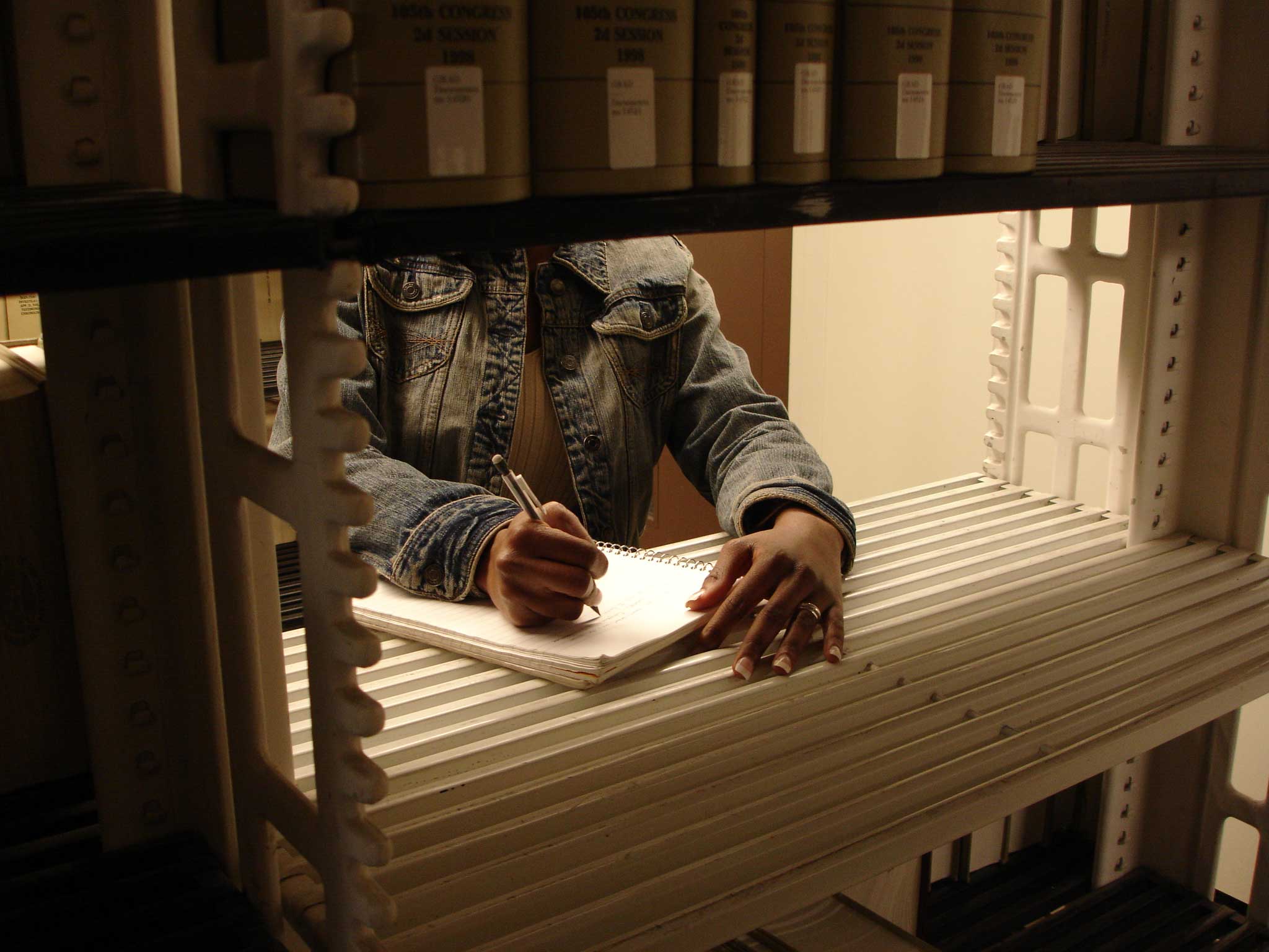 images of hands, writing, between shelves in the Graduate Library Stacks